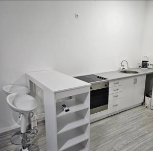 a white kitchen with a sink and a stool at Stan na dan Djogić in Nevesinje