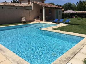 a swimming pool with blue chairs and a house at nice home rental in the hearth of the village mouriès, in the natural park of the alpilles in Mouriès