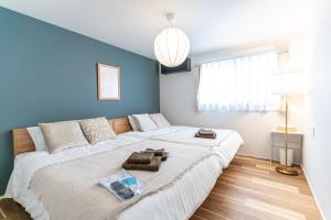 ein Schlafzimmer mit einem großen weißen Bett und einer blauen Wand in der Unterkunft みらいステイKawachi in Kumamoto