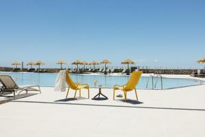 two chairs and a table in front of a pool at BANCAL HOTEL and SPA in San Sebastián de la Gomera