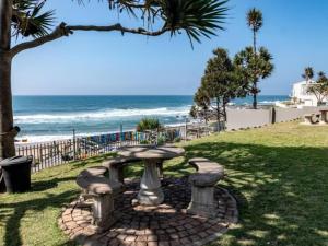 a stone bench in front of the beach at Idwala Tides 14 Casablanca Tri-Story Apartment - Ballito in Ballito