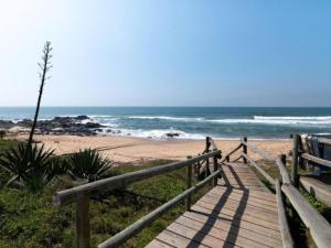 a wooden boardwalk leading to a beach with the ocean at Idwala Tides 14 Casablanca Tri-Story Apartment - Ballito in Ballito +1 photo