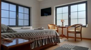 a bedroom with a bed and a table and windows at Klok Boutique `Otel in Seini