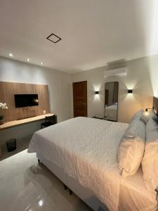 a bedroom with a large white bed and a television at Luster Hotel in João Câmara +19 photos
