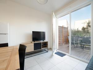 a living room with a television and a balcony at La Dune 38 - Villa 3P6 in Valras-Plage