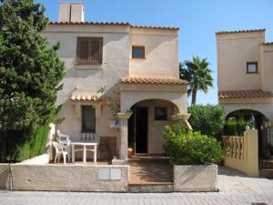 una casa con due sedie bianche davanti di Tranquila casa de vacaciones con terraza R139 by Novadesta a Gran Alacant