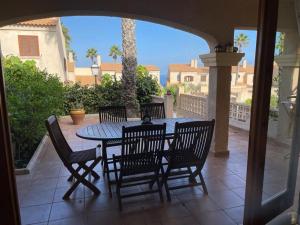 un patio con tavolo e sedie su un portico di Tranquila casa de vacaciones con terraza R139 by Novadesta a Gran Alacant
