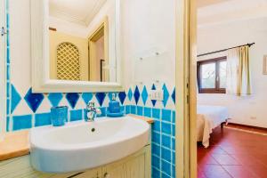 un bagno con lavandino bianco e piastrelle blu di Residence Con Spiaggia Privata Lettini e Ombrelloni Gratuiti a Porto Cervo Altre 83 foto