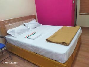 a bed with two towels and a blanket on it at Manasa Inn in Palakkad