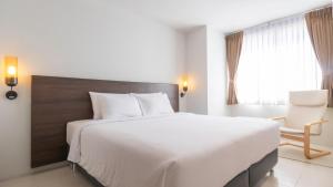 a bedroom with a large white bed and a chair at Pas Cher Hotel de Bangkok in Bangkok