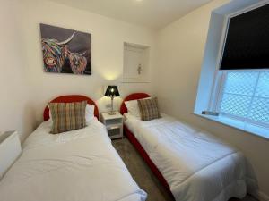 two beds in a small room with a window at Pass the Keys Stunning Cosy Cottage in Historic Moffat in Moffat