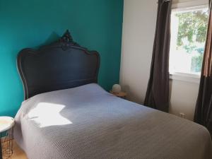 a bedroom with a bed with a black headboard and a window at Pleasant part of house with pool to share in Vaucluse, 4/6 people in Puget
