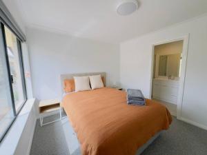 WilliamstownNew Unit On Oswald的一间卧室配有一张带橙色毯子的大床
