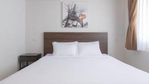 a bedroom with a white bed with a wooden headboard at Pas Cher Hotel de Bangkok in Bangkok