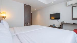 a hotel room with a white bed and a tv at Pas Cher Hotel de Bangkok in Bangkok