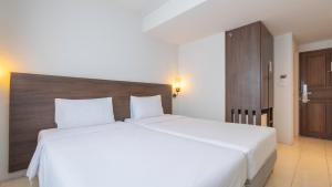 a bedroom with a large white bed with a wooden headboard at Pas Cher Hotel de Bangkok in Bangkok