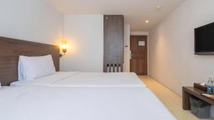 a bedroom with a large white bed and a television at Pas Cher Hotel de Bangkok in Bangkok