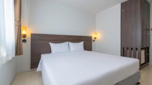a bedroom with a large white bed with a wooden headboard at Pas Cher Hotel de Bangkok in Bangkok