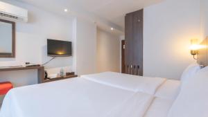 a bedroom with a white bed and a television at Pas Cher Hotel de Bangkok in Bangkok