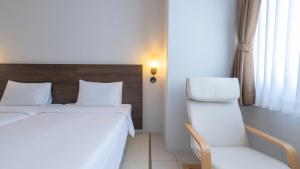 a hotel room with two beds and a chair at Pas Cher Hotel de Bangkok in Bangkok
