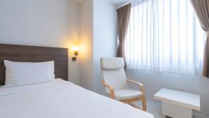 a bedroom with a bed and a chair and a window at Pas Cher Hotel de Bangkok in Bangkok