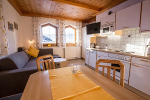 a kitchen and a living room with a table and a couch at Aparthaus Birkenheim in Filzmoos