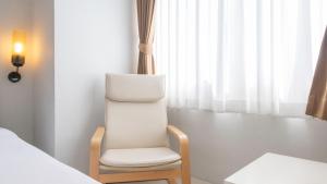 a white chair in a room with a bed at Pas Cher Hotel de Bangkok in Bangkok