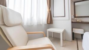 a white room with a chair and a table at Pas Cher Hotel de Bangkok in Bangkok