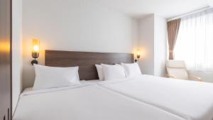 a bedroom with a large white bed and a window at Pas Cher Hotel de Bangkok in Bangkok