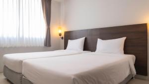 two beds in a hotel room with white sheets at Pas Cher Hotel de Bangkok in Bangkok