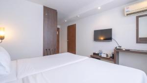 a bedroom with a white bed and a tv at Pas Cher Hotel de Bangkok in Bangkok
