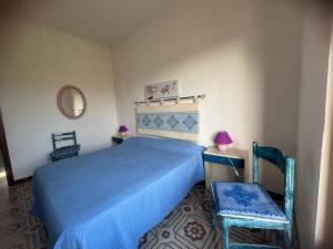 a bedroom with a blue bed and two chairs at Sa domo manna in Porto Ottiolu