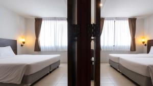 a hotel room with two beds and two windows at Pas Cher Hotel de Bangkok in Bangkok