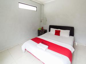 Un dormitorio con una gran cama blanca con almohadas rojas. en RedDoorz at Penginapan Hello Pacitan, en Pacitan