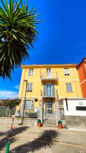 a yellow building with a palm tree in front of it at Affittacamere Les chambres in Chiavari