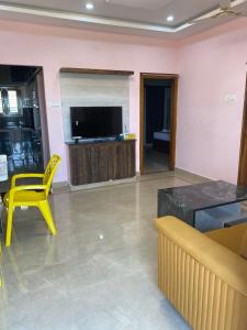 ティルパティにあるAthidi Luxury Home Stay - AC 2BHK Fully Furnished Flat with TV, WI-FI, 24Hrs Hot water, Parking, Elevator, Power Backupのリビングルーム(黄色い椅子、テレビ付)