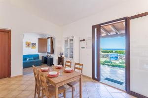 a dining room and living room with a table and chairs at La Casa Azzurra in Tertenìa
