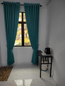 瓜拉丁加奴MAA Roomstay B的一张带蓝色窗帘的窗户,位于带桌子的房间