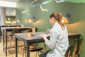 una mujer sentada en una mesa en un restaurante en Holiday Inn - the niu, Amity Potsdam by IHG, en Potsdam