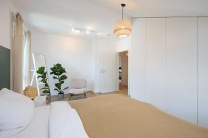 a white bedroom with a bed and a chair at Ferienwohnung zum Hochgarten in Krün +9 photos