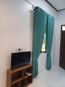 a living room with green curtains and a tv at MAA Roomstay C in Kuala Terengganu