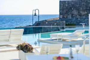 卡列罗港Royal Marina Suites Boutique Hotel - Adults Only的一个带白色椅子的游泳池以及大海