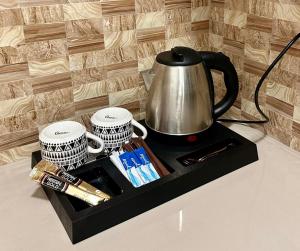 a tray with a tea kettle and two cups on a counter at Lydelles Guesthouse in Butuan