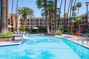 a pool in front of a hotel with palm trees at Grand Legacy At The Park in Anaheim