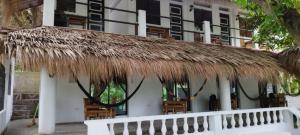 a straw roof on a building with chairs at Dumaguete divers rooms in Dauin
