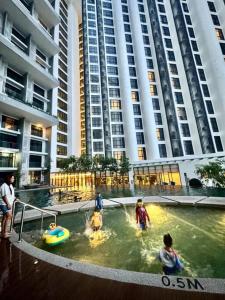a group of people playing in a pool in front of buildings at The Shore Suite seaview balcony Free Wifi & Netflix in Kota Kinabalu