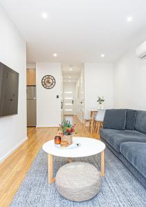 een woonkamer met een bank en een tafel bij Chic Flinders Park Getaway in Adelaide