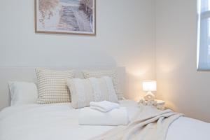 een witte slaapkamer met een wit bed met kussens bij Chic Flinders Park Getaway in Adelaide