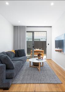 een woonkamer met een bank en een tafel bij Chic Flinders Park Getaway in Adelaide