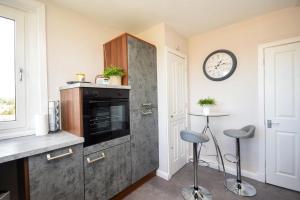 une cuisine avec une cuisinière et une horloge au mur dans l'établissement Laudervale East Penthouse Loch Lomond, à Balloch